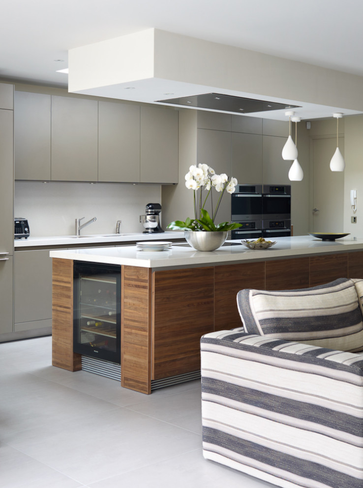 Large contemporary galley kitchen in London with a submerged sink, flat-panel cabinets, grey cabinets, white splashback, integrated appliances, porcelain flooring, an island, grey floors and white worktops.