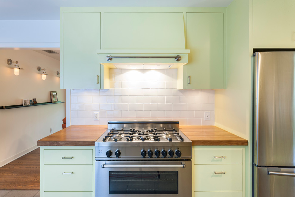 Foto di una cucina contemporanea con top in legno, ante gialle, ante lisce, paraspruzzi bianco, paraspruzzi con piastrelle diamantate e elettrodomestici in acciaio inossidabile