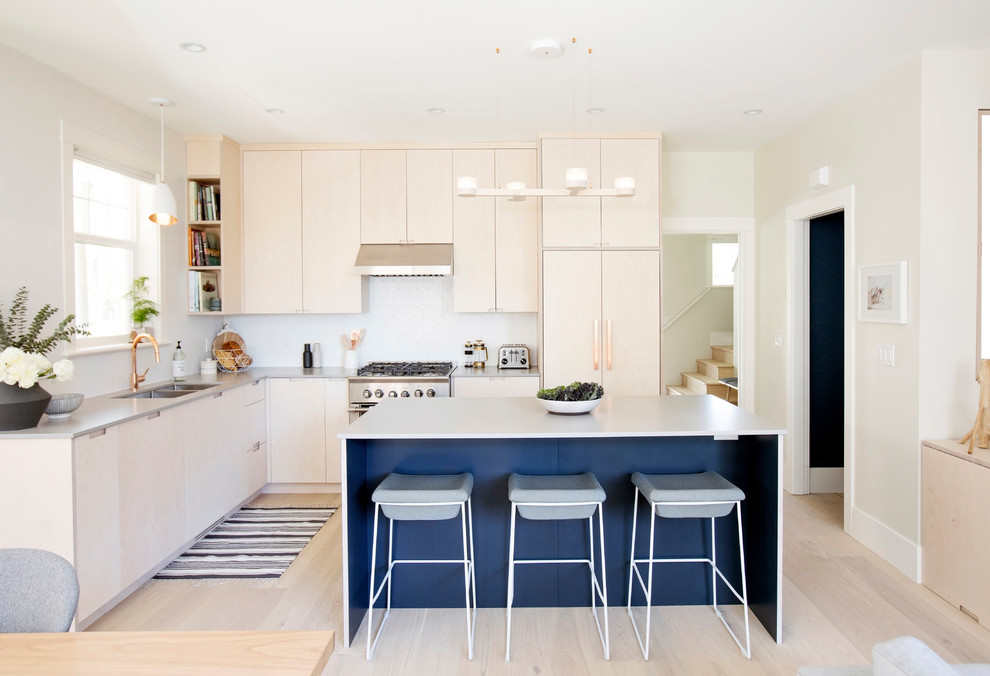Small scandinavian l-shaped open plan kitchen in Vancouver with a double-bowl sink, flat-panel cabinets, light wood cabinets, engineered stone countertops, white splashback, porcelain splashback, stainless steel appliances, light hardwood flooring, an island, grey worktops and beige floors.