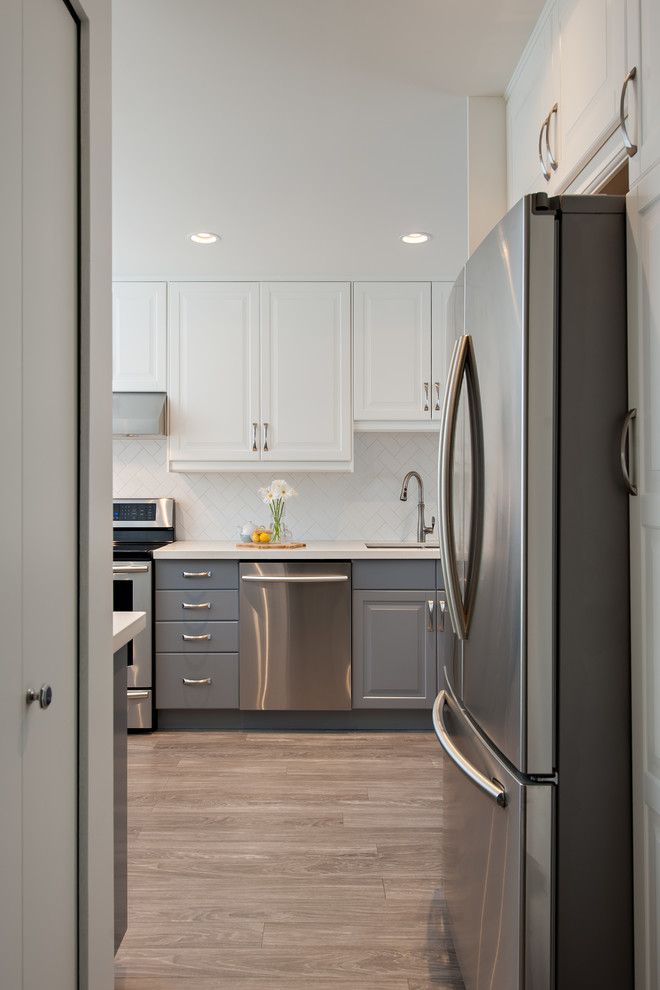 Photo of a traditional grey and white u-shaped enclosed kitchen in Vancouver with a double-bowl sink, engineered stone countertops, white splashback, metro tiled splashback, stainless steel appliances and no island.
