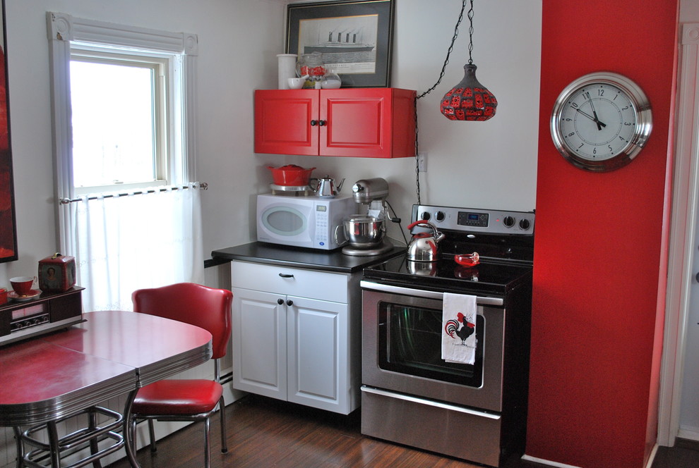 Bild på ett eklektiskt kök, med rostfria vitvaror och röda skåp
