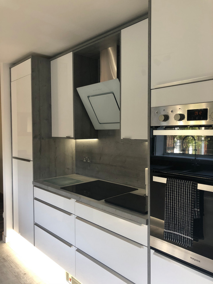 Inspiration for a medium sized contemporary kitchen/diner in Glasgow with an integrated sink, flat-panel cabinets, white cabinets, laminate countertops, grey splashback, wood splashback, stainless steel appliances, vinyl flooring, no island, grey floors and grey worktops.
