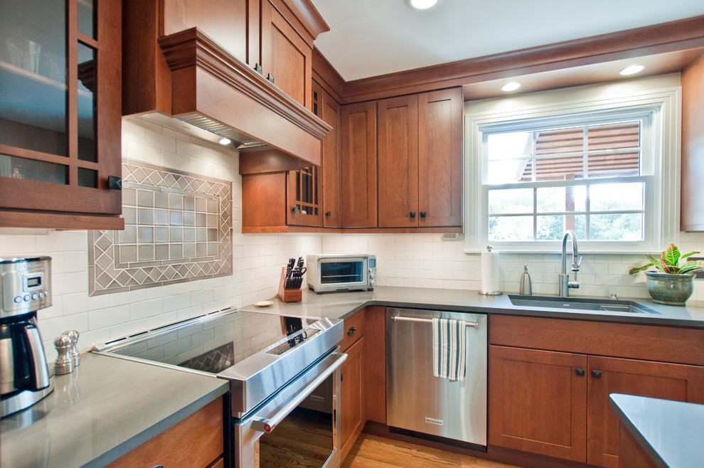 Mid-sized arts and crafts l-shaped light wood floor and brown floor kitchen photo in Nashville with a single-bowl sink, shaker cabinets, medium tone wood cabinets, quartz countertops, white backsplash, subway tile backsplash, stainless steel appliances, an island and gray countertops