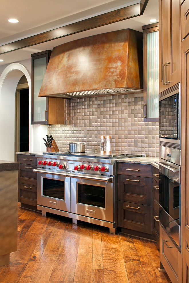 Immagine di una cucina con paraspruzzi multicolore, paraspruzzi con piastrelle in pietra, elettrodomestici da incasso, pavimento in legno massello medio e 2 o più isole