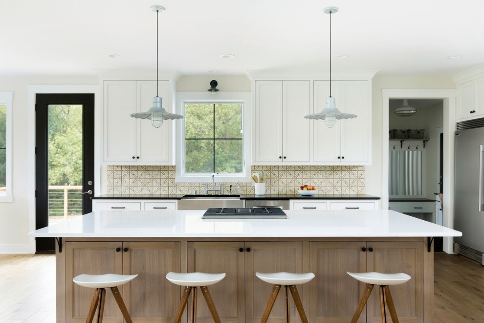 Inspiration for a farmhouse kitchen in Minneapolis with a belfast sink, shaker cabinets, white cabinets, multi-coloured splashback, light hardwood flooring, an island and beige floors.
