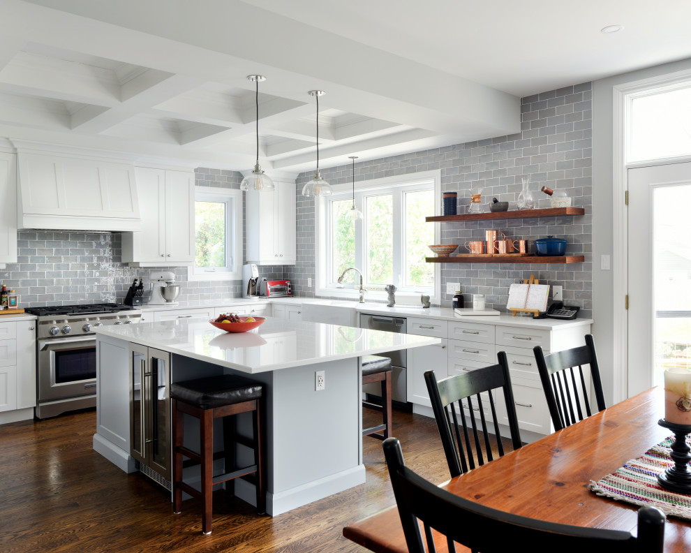 Transitional u-shaped dark wood floor and brown floor eat-in kitchen photo in Ottawa with a farmhouse sink, shaker cabinets, white cabinets, gray backsplash, stainless steel appliances, an island and white countertops