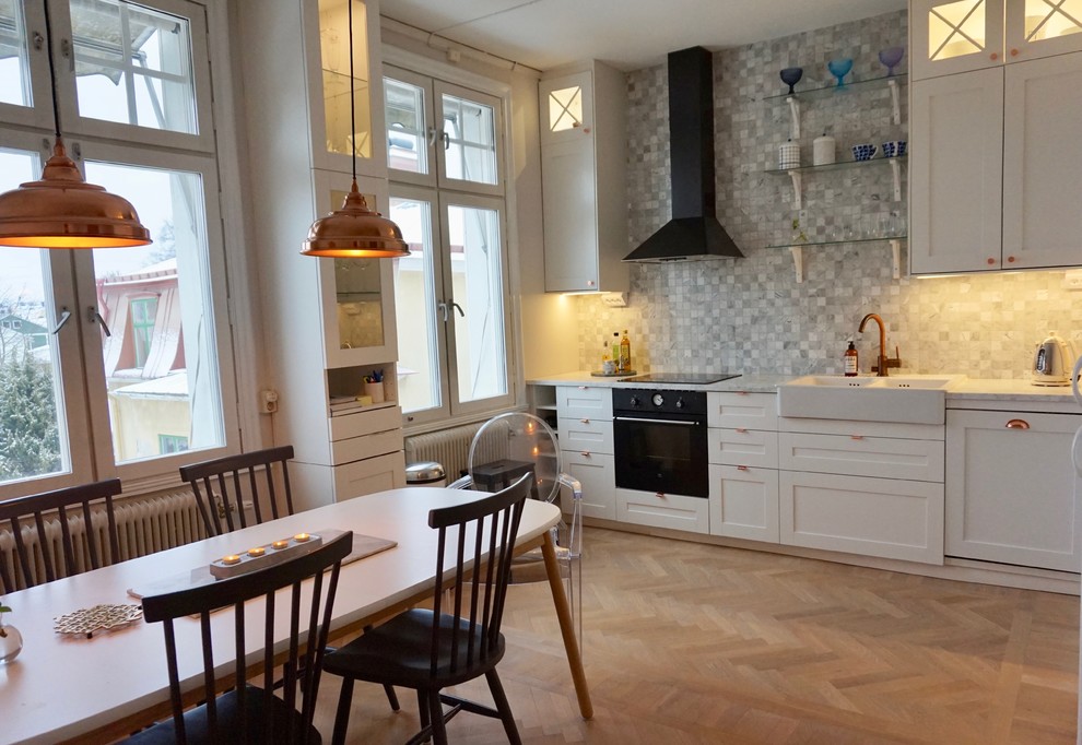 Idéer för ett mellanstort klassiskt grå linjärt kök och matrum, med en rustik diskho, skåp i shakerstil, vita skåp, marmorbänkskiva, grått stänkskydd, stänkskydd i marmor, svarta vitvaror, ljust trägolv och beiget golv