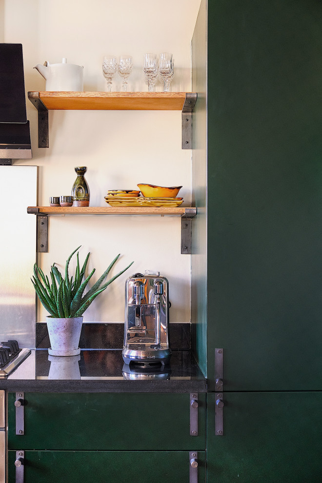 This is an example of a medium sized retro u-shaped open plan kitchen in London with a single-bowl sink, flat-panel cabinets, green cabinets, marble worktops, stainless steel appliances, dark hardwood flooring, no island, brown floors and black worktops.