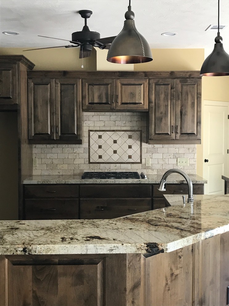 Photo of a medium sized rustic l-shaped open plan kitchen in Austin with raised-panel cabinets, dark wood cabinets, granite worktops, grey splashback, stone tiled splashback and an island.