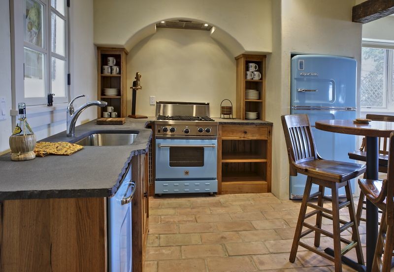 Bild på ett mellanstort rustikt kök, med en undermonterad diskho, öppna hyllor, skåp i mellenmörkt trä, bänkskiva i betong, rostfria vitvaror, tegelgolv och brunt golv