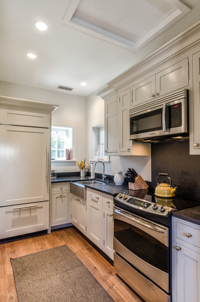 Urige Küche mit Landhausspüle, Schrankfronten im Shaker-Stil, beigen Schränken und Küchenrückwand in Schwarz in New York