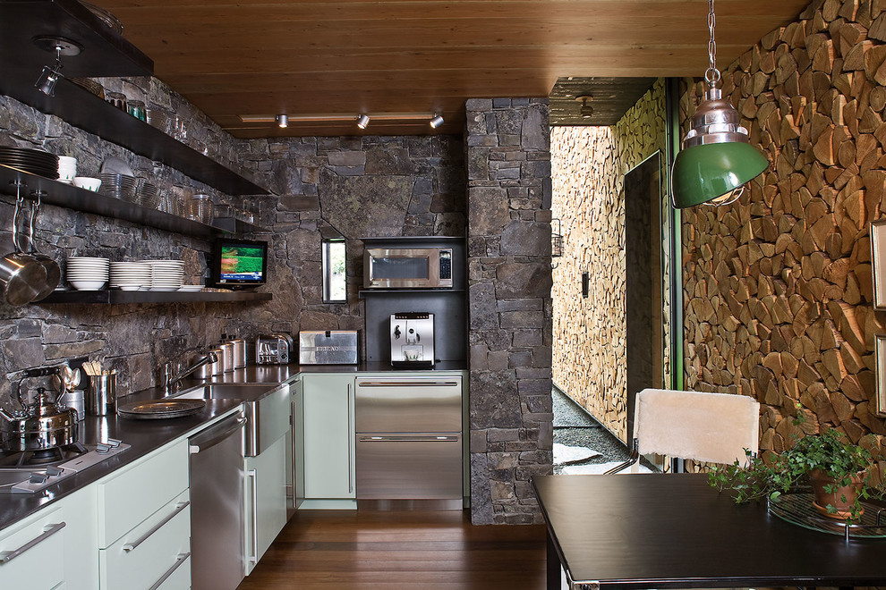 Exempel på ett avskilt, mellanstort rustikt l-kök, med en rustik diskho, släta luckor, grå skåp, grått stänkskydd, stänkskydd i stenkakel, mellanmörkt trägolv och rostfria vitvaror