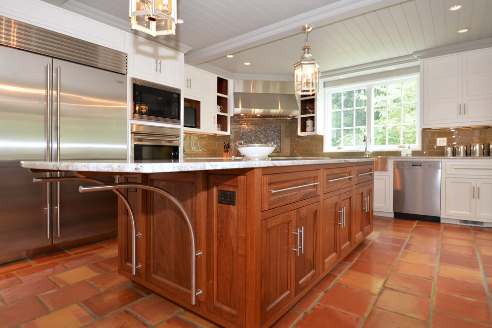 Inspiration for a large country l-shaped open plan kitchen in New York with a belfast sink, shaker cabinets, white cabinets, marble worktops, brown splashback, metro tiled splashback, stainless steel appliances, terracotta flooring and an island.