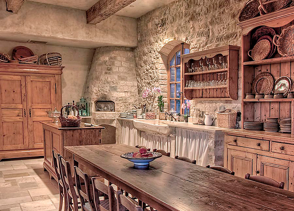Inspiration for a large mediterranean l-shaped limestone floor eat-in kitchen remodel in Los Angeles with a farmhouse sink, flat-panel cabinets, distressed cabinets, limestone countertops, beige backsplash, stone tile backsplash, white appliances and two islands