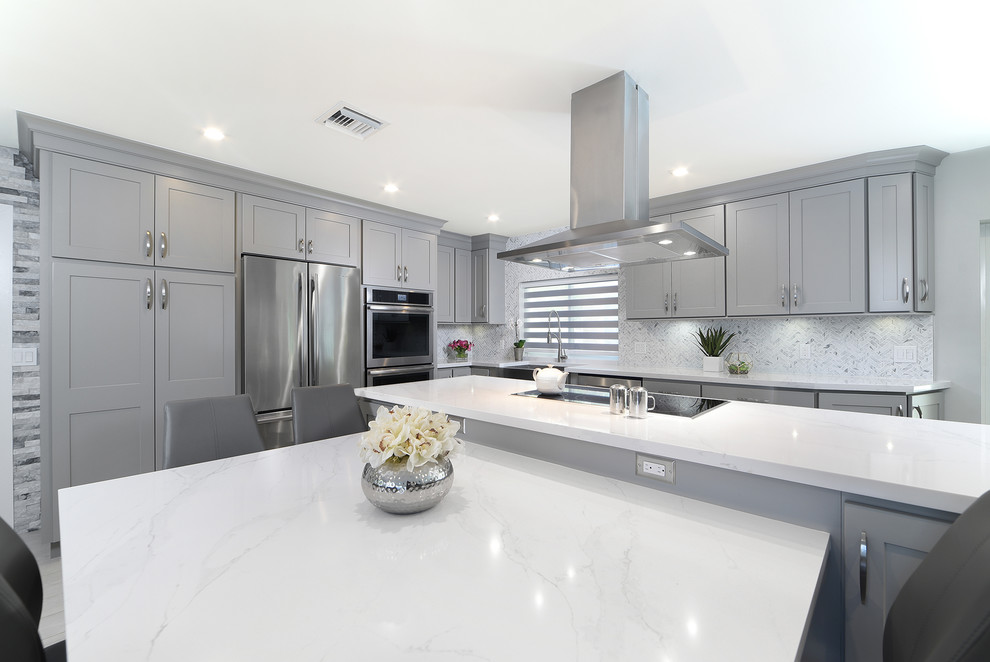 Inspiration for a large transitional l-shaped porcelain tile and gray floor open concept kitchen remodel in Miami with a farmhouse sink, shaker cabinets, gray cabinets, quartz countertops, gray backsplash, marble backsplash, stainless steel appliances and two islands