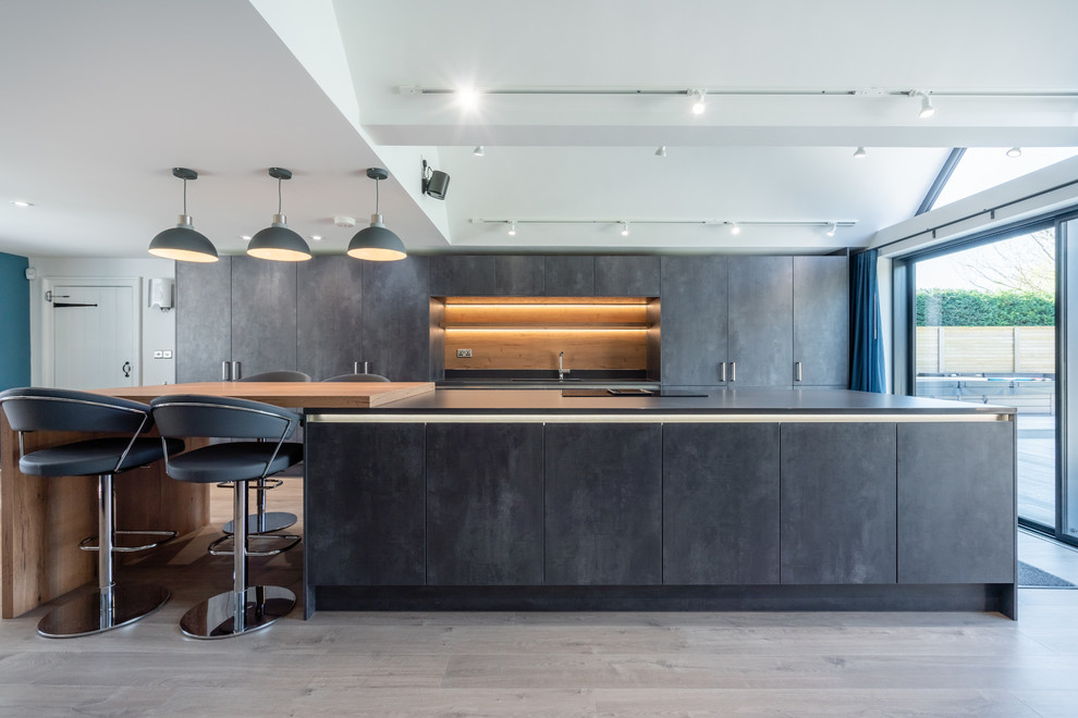 Idee per un ampio cucina con isola centrale minimalista con ante lisce, ante grigie, parquet chiaro, pavimento beige e top grigio