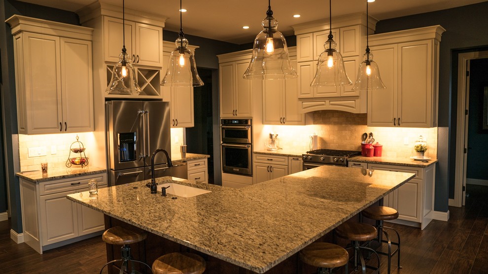 Bild på ett stort vintage flerfärgad flerfärgat kök, med en undermonterad diskho, luckor med upphöjd panel, vita skåp, granitbänkskiva, beige stänkskydd, stänkskydd i travertin, rostfria vitvaror, mörkt trägolv, en köksö och brunt golv