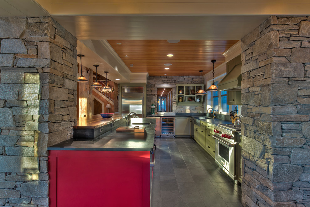 バーリントンにあるラスティックスタイルのおしゃれなアイランドキッチン (エプロンフロントシンク、シェーカースタイル扉のキャビネット、シルバーの調理設備、スレートの床) の写真