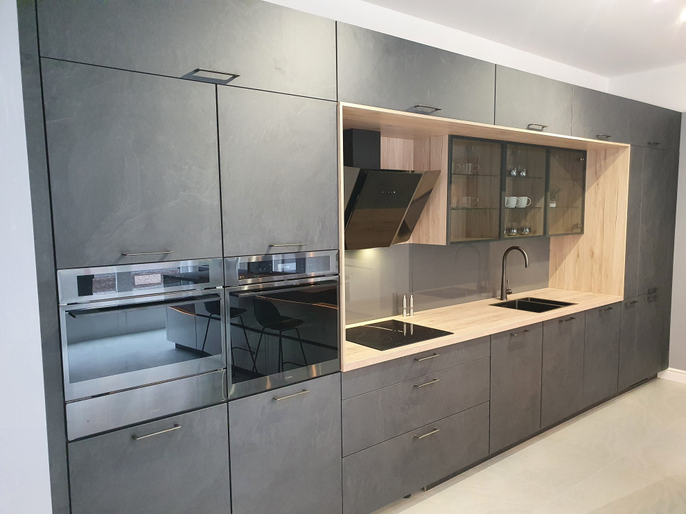 Photo of a medium sized contemporary single-wall kitchen/diner in Cheshire with a built-in sink, grey cabinets, wood worktops, grey splashback, glass sheet splashback, integrated appliances, porcelain flooring, no island and grey floors.