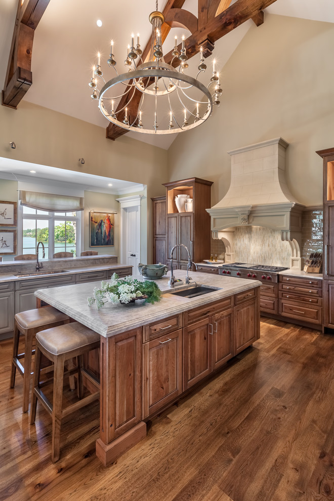 Inspiration for a huge timeless medium tone wood floor kitchen remodel in Other with an undermount sink, raised-panel cabinets, medium tone wood cabinets, quartzite countertops, beige backsplash, porcelain backsplash, an island and beige countertops
