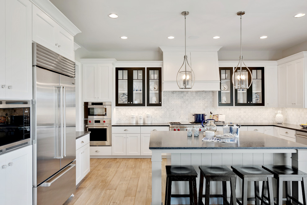 Design ideas for a large traditional u-shaped kitchen/diner in Chicago with shaker cabinets, white cabinets, grey splashback, stainless steel appliances, light hardwood flooring, an island and beige floors.