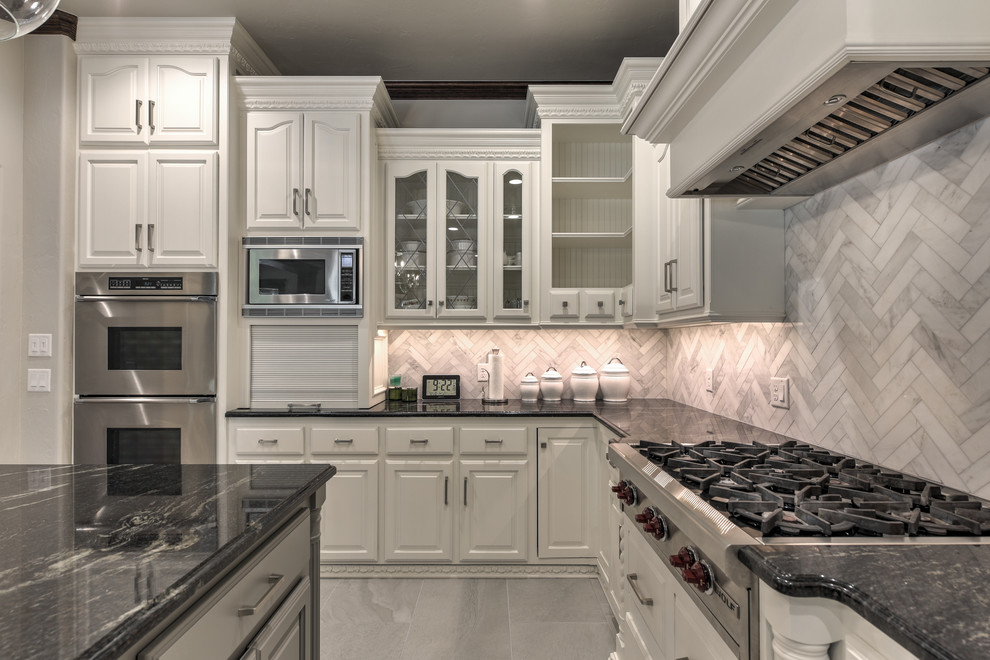 Idéer för ett avskilt, stort amerikanskt u-kök, med en rustik diskho, luckor med upphöjd panel, vita skåp, marmorbänkskiva, beige stänkskydd, stänkskydd i stenkakel, integrerade vitvaror, en köksö och grått golv