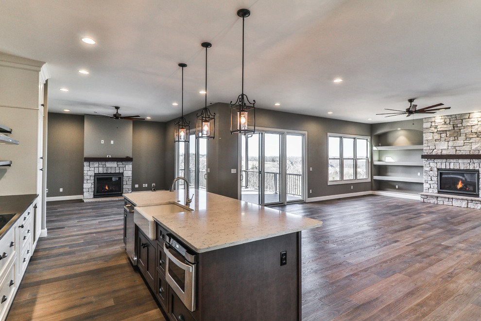 Inspiration for a large transitional single-wall dark wood floor and brown floor open concept kitchen remodel in St Louis with a farmhouse sink, shaker cabinets, white cabinets, quartzite countertops, stainless steel appliances and an island