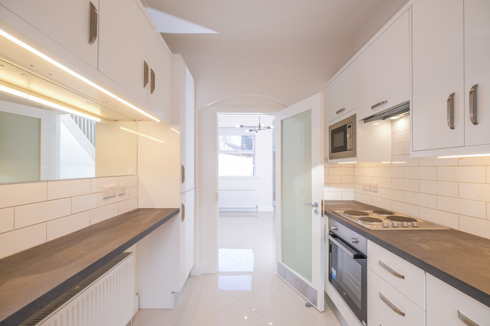 Geschlossene, Zweizeilige Moderne Küche mit flächenbündigen Schrankfronten, weißen Schränken und Porzellan-Bodenfliesen in Dublin