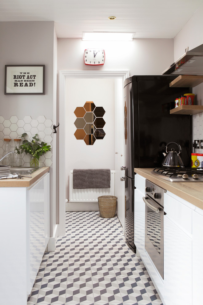 На фото: кухня в скандинавском стиле с накладной мойкой, плоскими фасадами, белыми фасадами, белым фартуком и черной техникой с