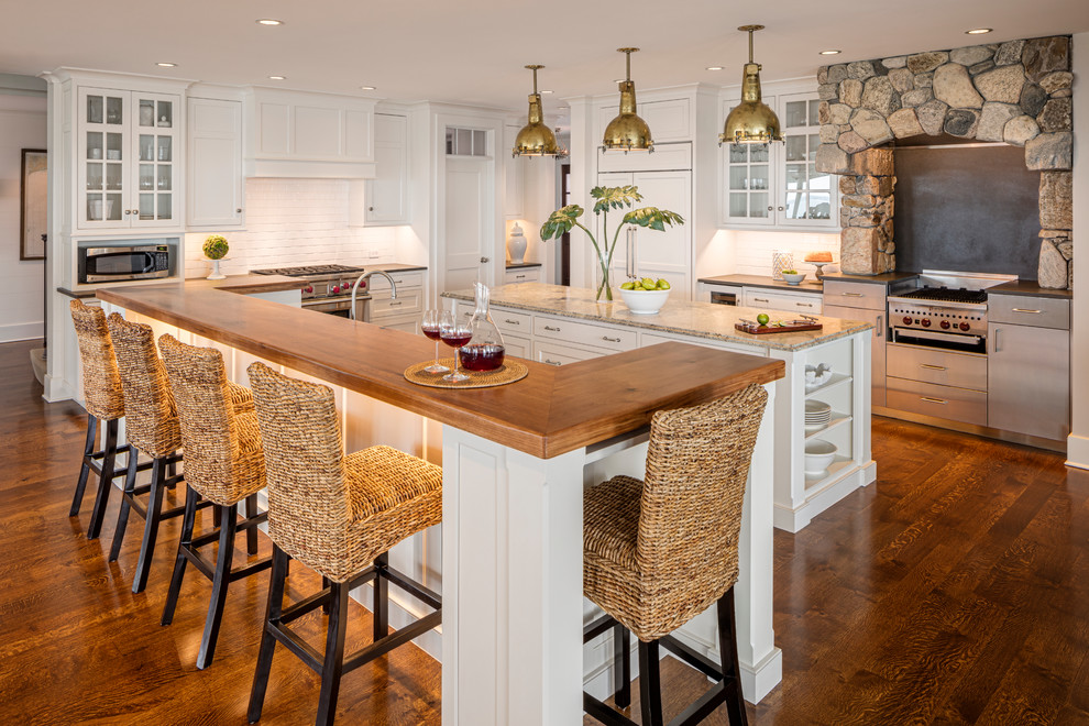 Imagen de cocina clásica renovada con armarios estilo shaker, puertas de armario blancas, salpicadero blanco, salpicadero de azulejos tipo metro, suelo de madera oscura, dos o más islas, encimera de madera, electrodomésticos de acero inoxidable y suelo marrón