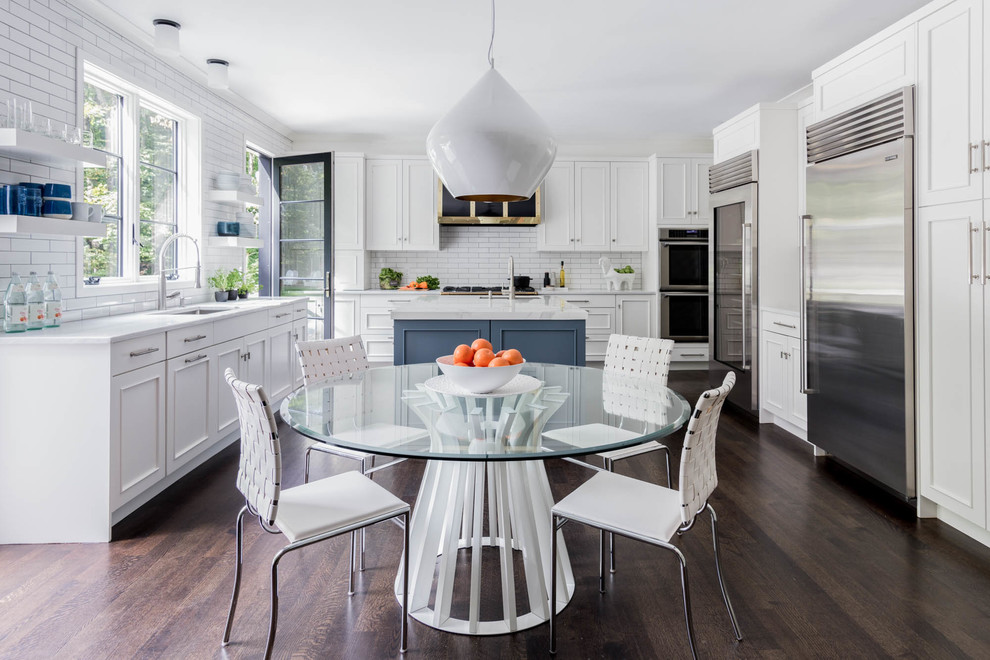 Design ideas for a classic u-shaped kitchen/diner in New York with a submerged sink, recessed-panel cabinets, white cabinets, white splashback, stainless steel appliances, dark hardwood flooring, an island and brown floors.