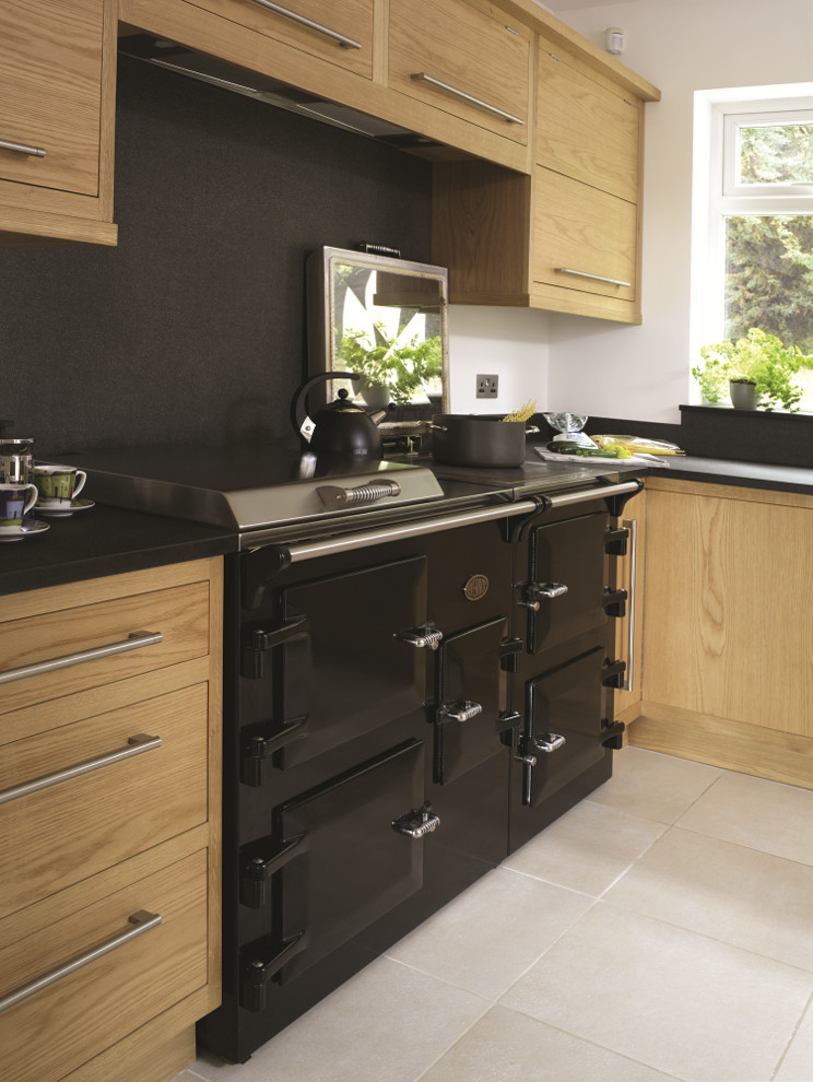 This is an example of a small modern galley enclosed kitchen in Surrey with a belfast sink, flat-panel cabinets, medium wood cabinets, granite worktops, stainless steel appliances and no island.