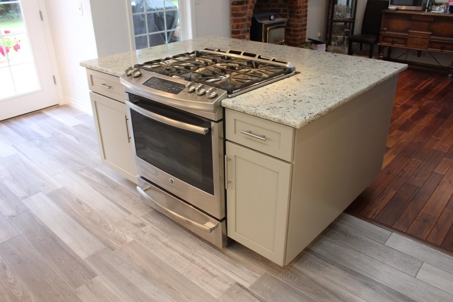 Inspiration for a mid-sized contemporary l-shaped vinyl floor open concept kitchen remodel in Seattle with an undermount sink, shaker cabinets, white cabinets, granite countertops, matchstick tile backsplash, stainless steel appliances and an island