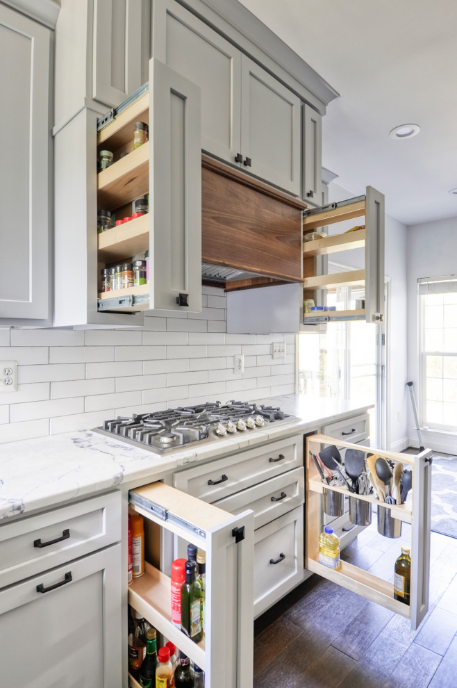 Example of a mid-sized country u-shaped dark wood floor and brown floor eat-in kitchen design in DC Metro with an undermount sink, recessed-panel cabinets, gray cabinets, quartz countertops, white backsplash, subway tile backsplash, stainless steel appliances, an island and white countertops