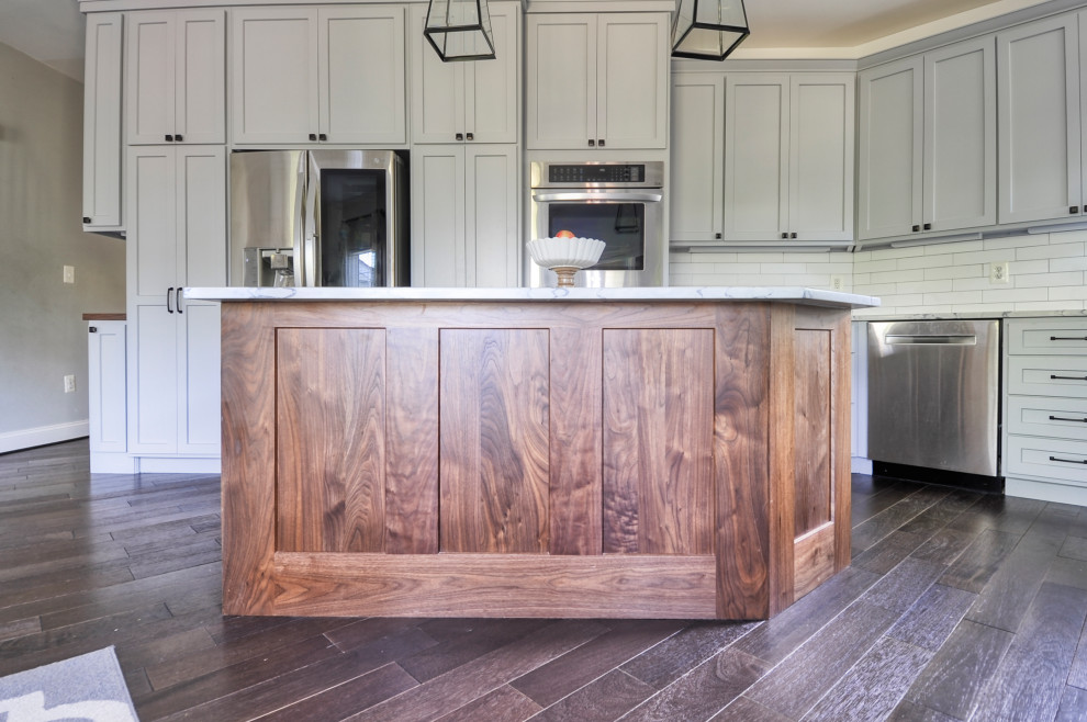 Inspiration for a mid-sized farmhouse u-shaped dark wood floor and brown floor eat-in kitchen remodel in DC Metro with an undermount sink, recessed-panel cabinets, gray cabinets, quartz countertops, white backsplash, subway tile backsplash, stainless steel appliances, an island and white countertops