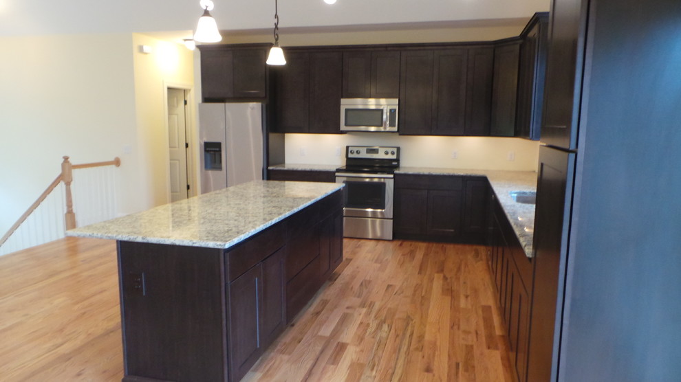Foto di una cucina di medie dimensioni con lavello sottopiano, ante in stile shaker, ante in legno bruno, top in granito, elettrodomestici in acciaio inossidabile e parquet chiaro