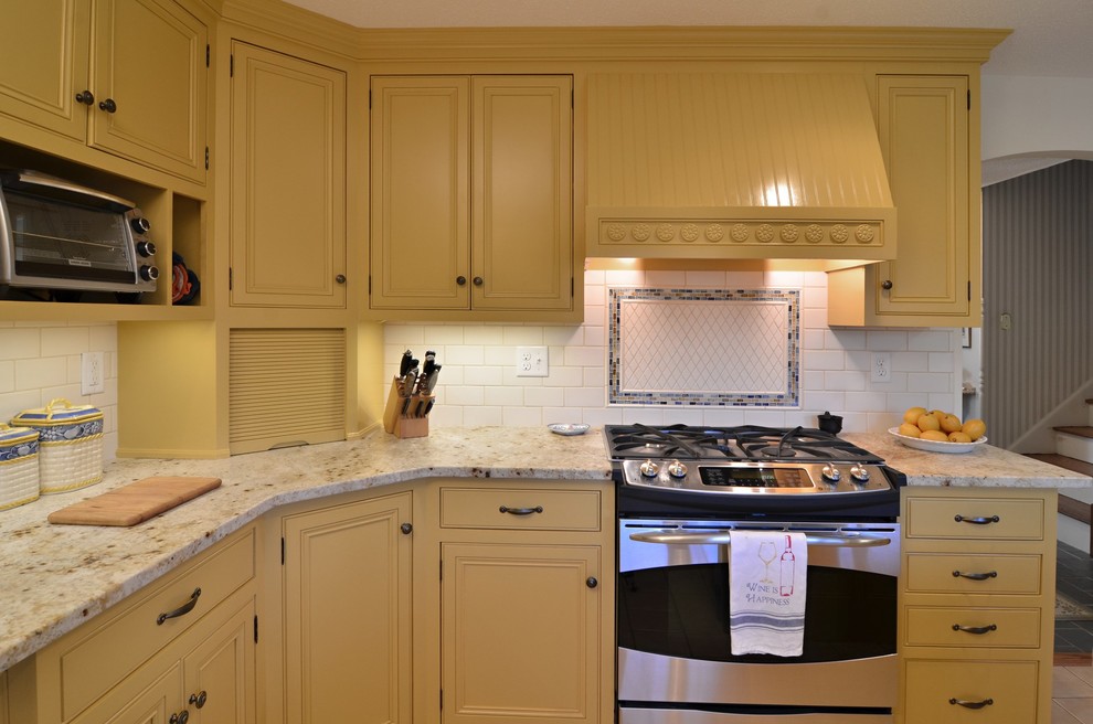 Bild på ett avskilt, stort vintage u-kök, med en halv köksö, luckor med profilerade fronter, gula skåp, granitbänkskiva, vitt stänkskydd, stänkskydd i tunnelbanekakel, rostfria vitvaror, en dubbel diskho och klinkergolv i keramik