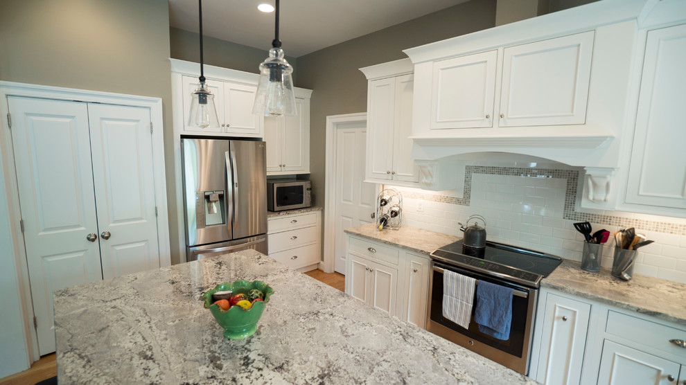 Eat-in kitchen - mid-sized traditional l-shaped light wood floor eat-in kitchen idea in DC Metro with a farmhouse sink, shaker cabinets, white cabinets, granite countertops, white backsplash, ceramic backsplash, stainless steel appliances and an island