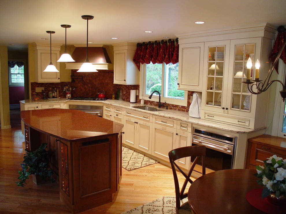Inspiration for a timeless light wood floor kitchen remodel in Boston with an undermount sink, recessed-panel cabinets, white cabinets, granite countertops, red backsplash, stainless steel appliances and an island