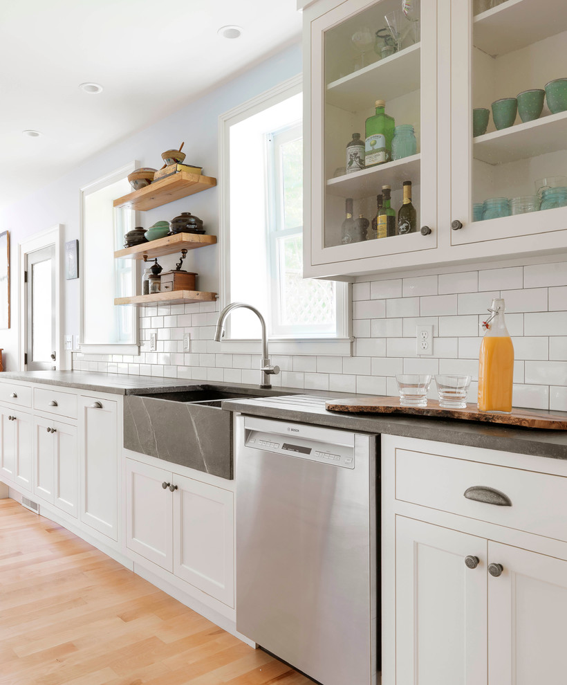 Country Küche mit Landhausspüle, Schrankfronten im Shaker-Stil, weißen Schränken, Küchenrückwand in Weiß, Rückwand aus Metrofliesen und braunem Holzboden in Burlington
