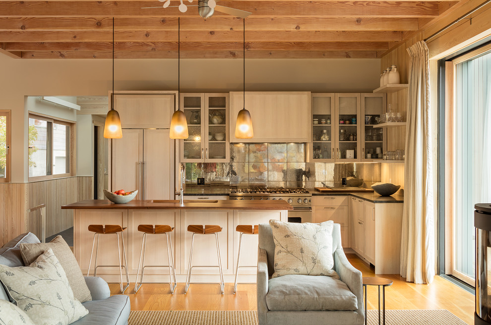 Cette image montre une cuisine ouverte encastrable design en L et bois clair avec un évier encastré, un placard à porte vitrée, une crédence métallisée, une crédence en dalle métallique, un sol en bois brun et îlot.