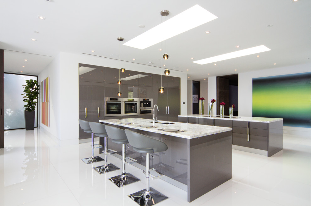 Foto på ett funkis kök, med en dubbel diskho, släta luckor, grå skåp, rostfria vitvaror, flera köksöar och vitt golv