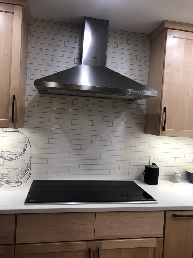 Example of a large trendy l-shaped light wood floor and beige floor eat-in kitchen design in Boston with a farmhouse sink, shaker cabinets, light wood cabinets, wood countertops, white backsplash, subway tile backsplash, stainless steel appliances, an island and brown countertops