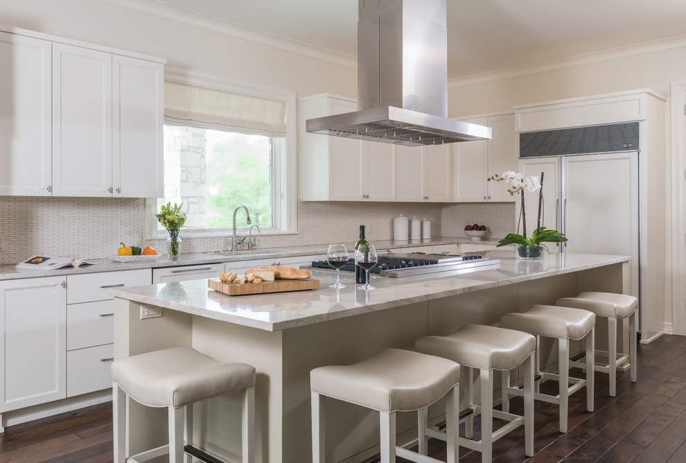 Inspiration for a large beach style l-shaped kitchen in Austin with shaker cabinets, white cabinets, beige splashback, integrated appliances, dark hardwood flooring, an island, a built-in sink, laminate countertops, ceramic splashback and brown floors.