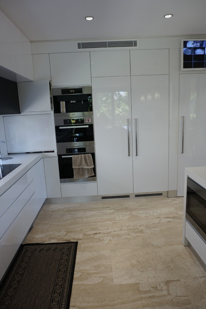 Design ideas for a medium sized modern l-shaped kitchen/diner in Sydney with a submerged sink, white cabinets, engineered stone countertops, stainless steel appliances, travertine flooring and an island.