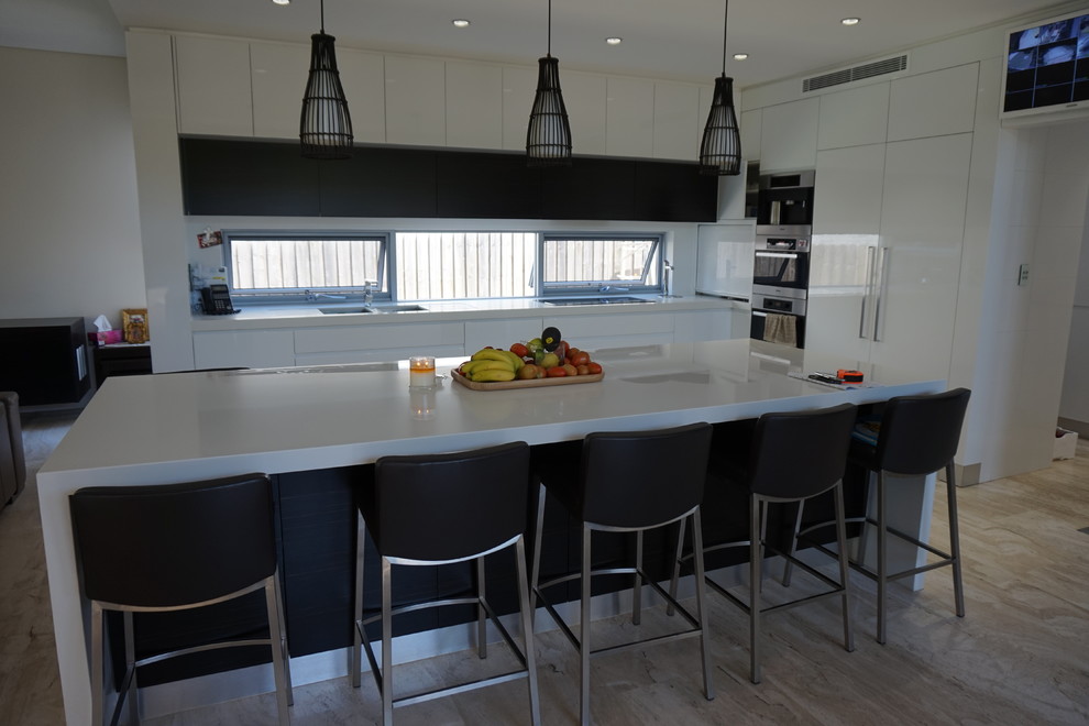 Mittelgroße Moderne Wohnküche in L-Form mit Unterbauwaschbecken, weißen Schränken, Quarzwerkstein-Arbeitsplatte, Küchengeräten aus Edelstahl, Travertin und Kücheninsel in Sydney