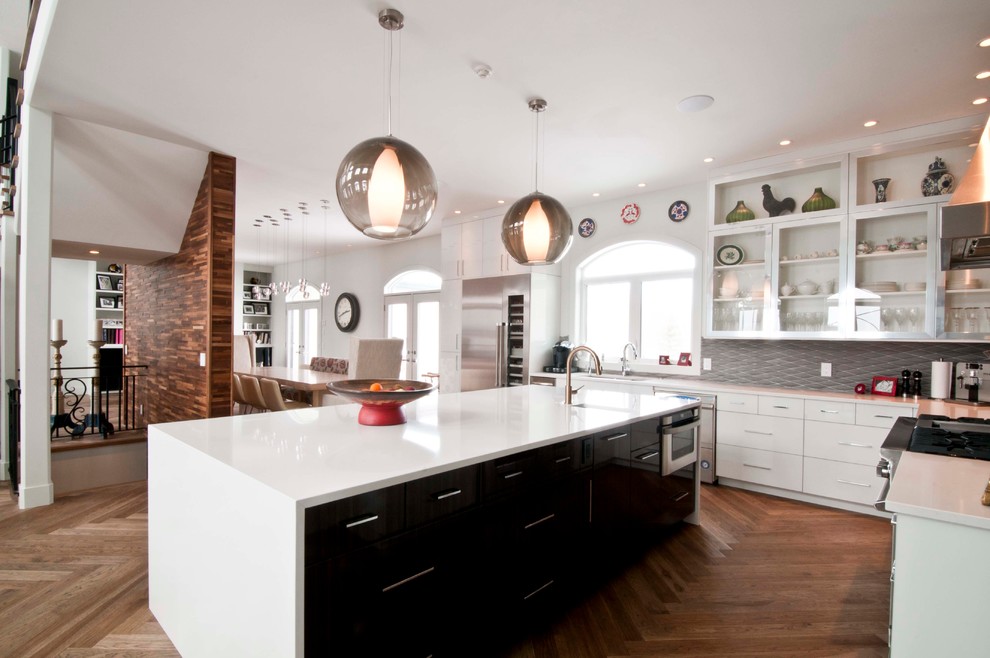 Example of a large l-shaped light wood floor eat-in kitchen design in Calgary with an island, flat-panel cabinets, white cabinets, quartzite countertops, gray backsplash, stone tile backsplash, stainless steel appliances and an undermount sink