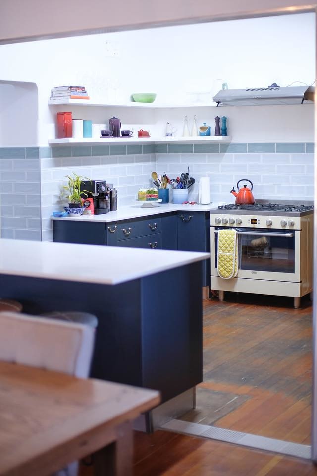 他の地域にある小さな北欧スタイルのおしゃれなキッチン (シングルシンク、フラットパネル扉のキャビネット、青いキャビネット、クオーツストーンカウンター、マルチカラーのキッチンパネル、サブウェイタイルのキッチンパネル、カラー調理設備、淡色無垢フローリング、茶色い床、白いキッチンカウンター) の写真