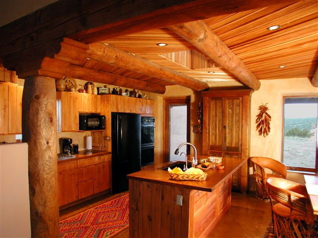 Bild på ett mellanstort amerikanskt brun linjärt brunt kök och matrum, med en undermonterad diskho, skåp i shakerstil, skåp i mellenmörkt trä, bänkskiva i akrylsten, svarta vitvaror, betonggolv, en köksö, beige stänkskydd och grått golv