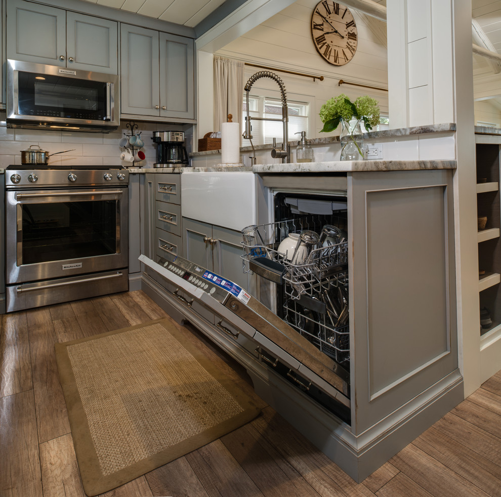 Inspiration for a small coastal u-shaped light wood floor and brown floor eat-in kitchen remodel in Detroit with a farmhouse sink, beaded inset cabinets, gray cabinets, granite countertops, white backsplash, subway tile backsplash, stainless steel appliances, no island and gray countertops